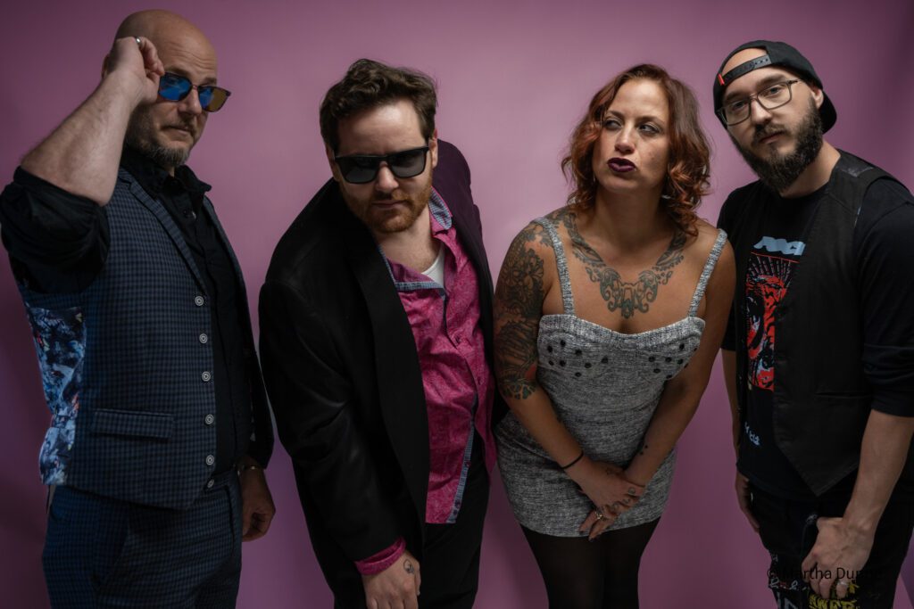 Bellwether Ritual band members posing for a group shot in front of a pink wall