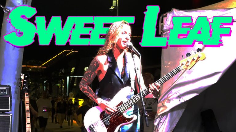 Sweet Leaf text behind Hilary signing the cover of the Black Sabbath song.